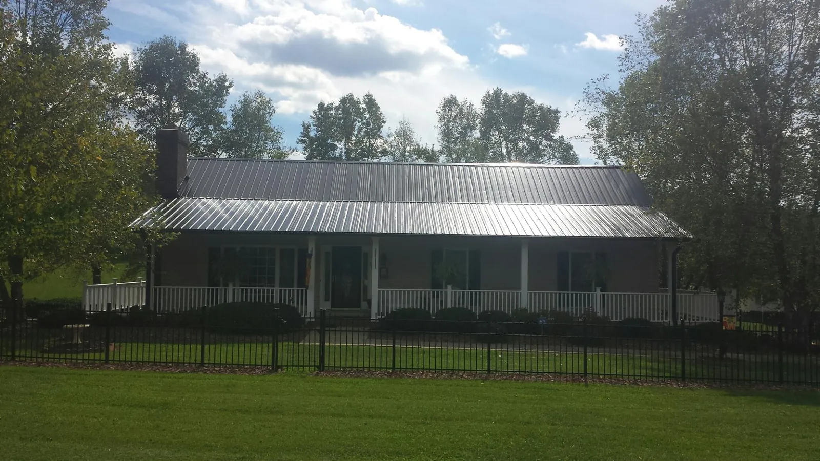 Gray metal roof on a brick ranch with a full width front porch — Gutter Guard Installation work by our crew in Union Grove