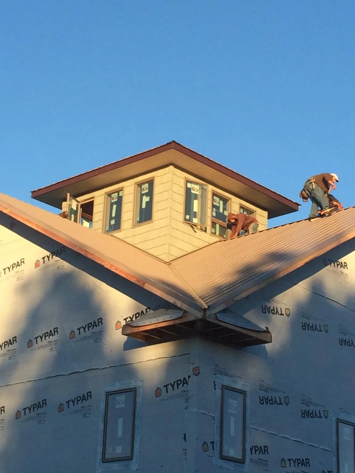 Roofers working around a rooftop cupola on a new metal roof at sunset — Roof Waterproofing in Union Grove by Roofing Brothers